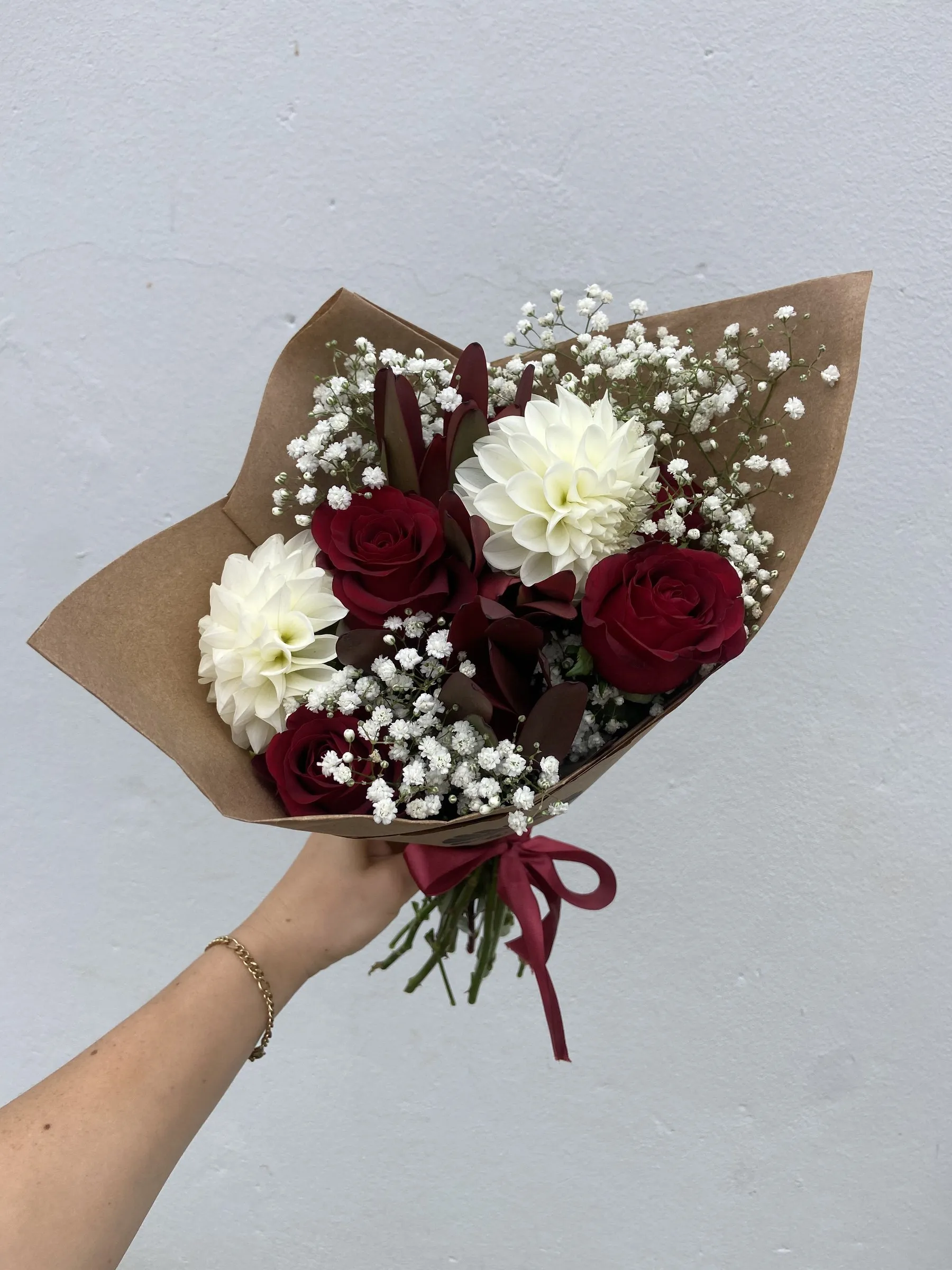 Deep red dahlias and white chrysanthemums in kraft paper, tied with red twine