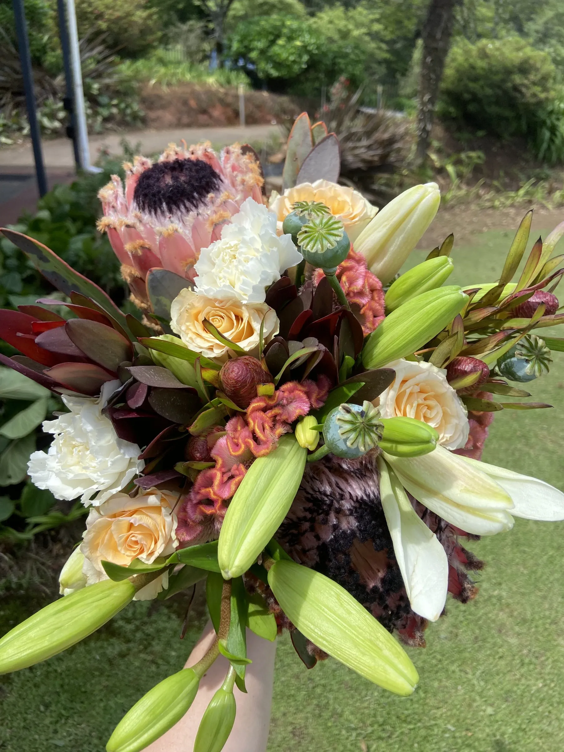 A large arrangement of king protea, lilies and roses in autumn tones