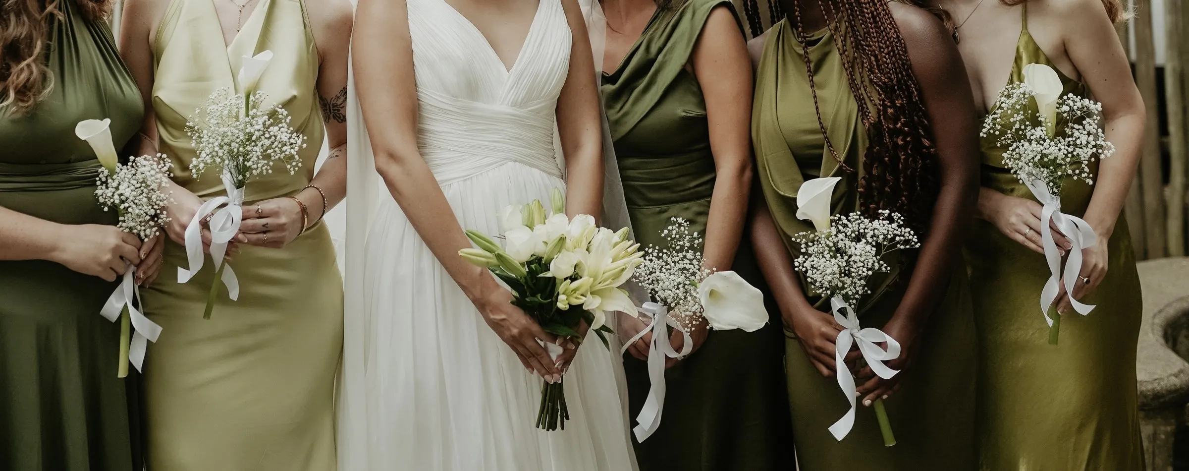 Bridesmaids in olive green holding white calla lily and gypsophila bouquets